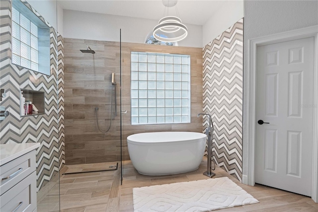 full bath with vanity, tile walls, a freestanding tub, and a tile shower