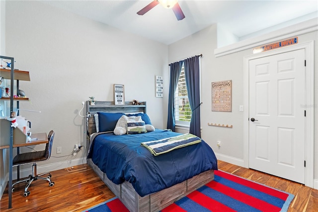 bedroom with a ceiling fan, wood finished floors, and baseboards