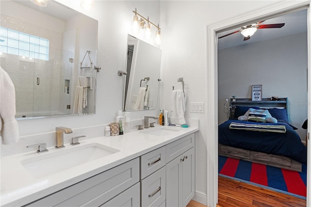 bathroom with a shower stall, connected bathroom, double vanity, and a sink