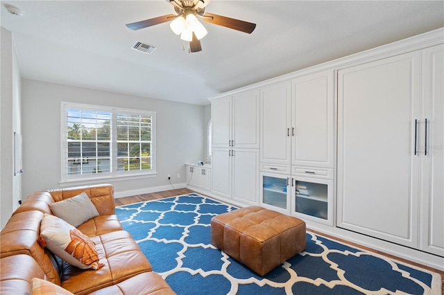 living area featuring a ceiling fan, wood finished floors, visible vents, and baseboards