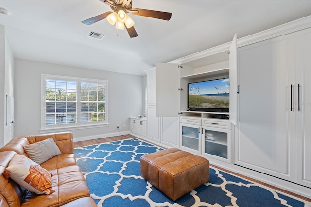 living area featuring visible vents, baseboards, wood finished floors, and a ceiling fan