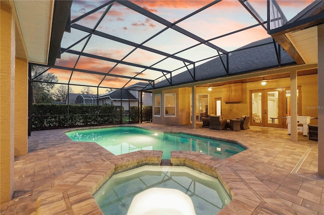 view of swimming pool with a lanai, french doors, a pool with connected hot tub, and a patio