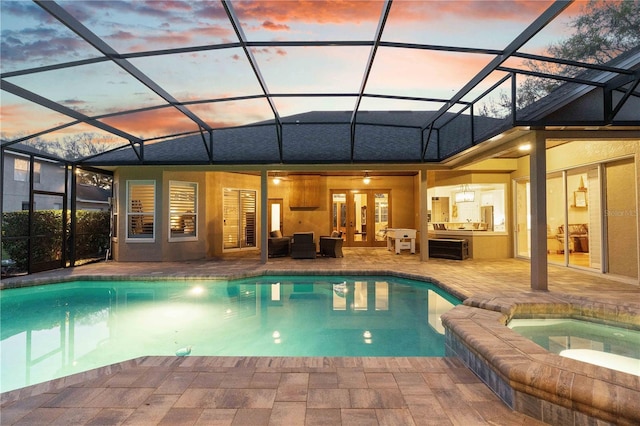 pool at dusk featuring glass enclosure, french doors, a pool with connected hot tub, and a patio