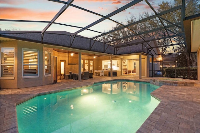 view of swimming pool featuring glass enclosure, a pool with connected hot tub, and a patio area