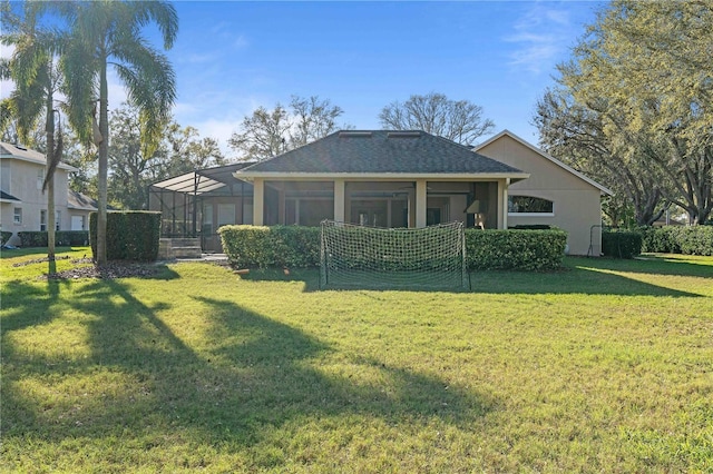 back of property featuring glass enclosure, stucco siding, a lawn, and a shingled roof