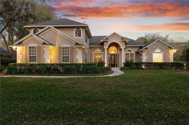 traditional home featuring stucco siding and a lawn