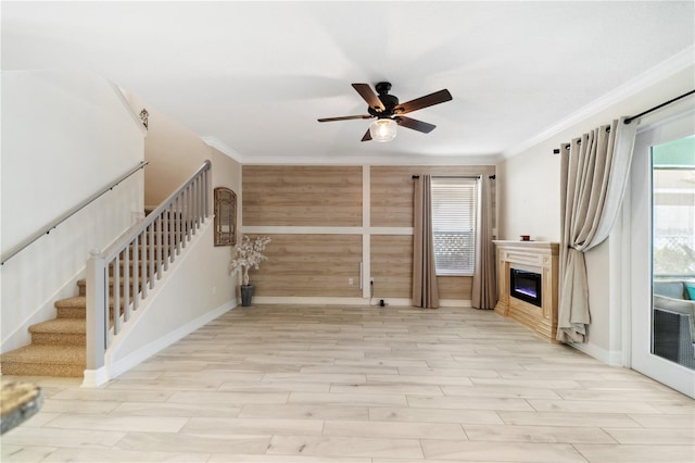 unfurnished living room featuring light wood finished floors, stairway, crown molding, and ceiling fan