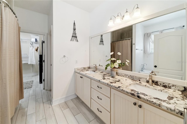 full bath with wood tiled floor, double vanity, baseboards, and a sink