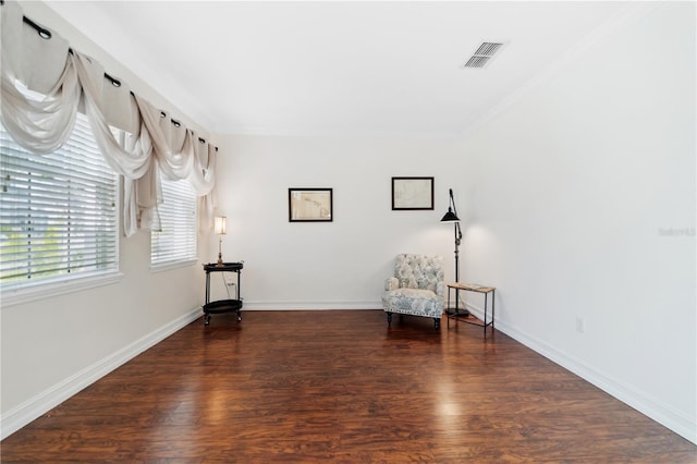 unfurnished room featuring crown molding, wood finished floors, visible vents, and baseboards