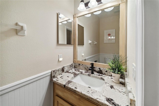 bathroom with vanity and a wainscoted wall