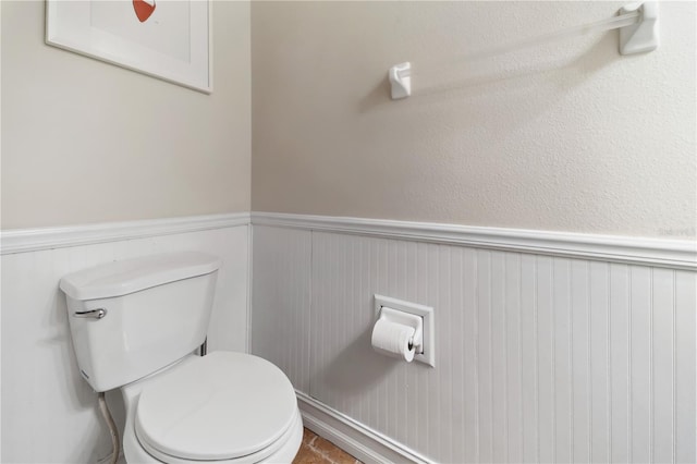 bathroom featuring a wainscoted wall and toilet