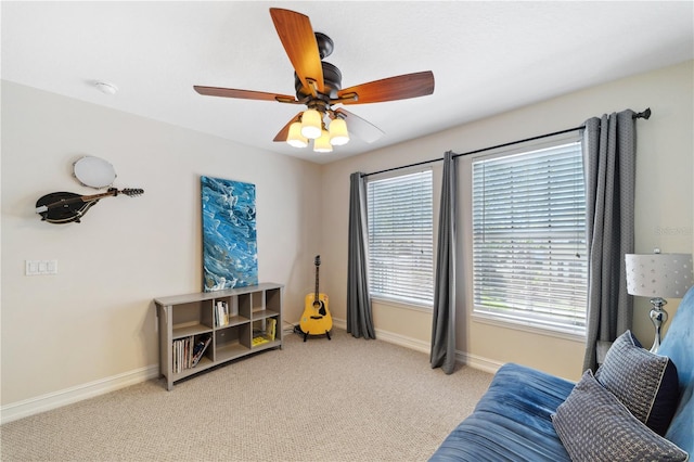 living area featuring baseboards, a ceiling fan, and carpet flooring