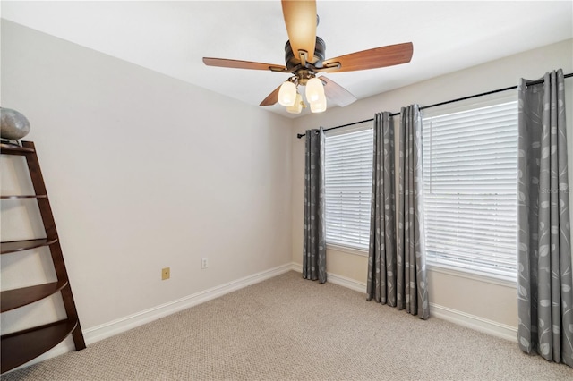 empty room featuring baseboards, carpet floors, and a ceiling fan