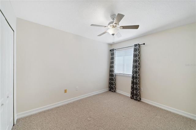 carpeted spare room with baseboards and ceiling fan