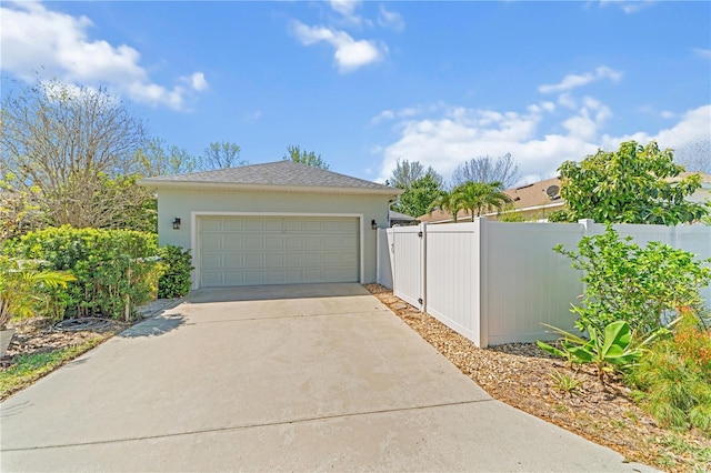 garage featuring a gate, driveway, and fence