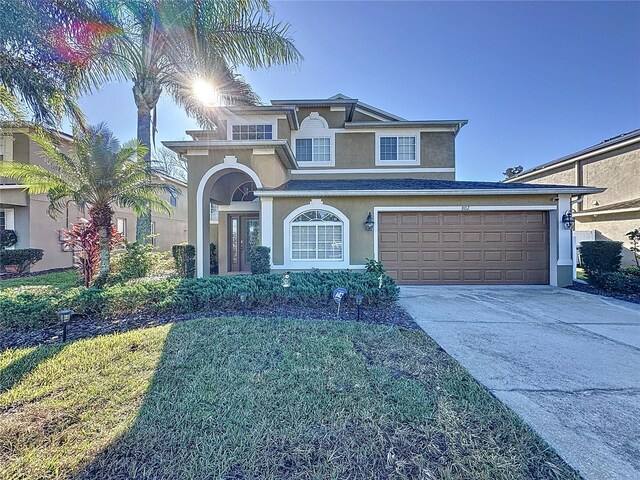 traditional-style house featuring stucco siding, a front lawn, concrete driveway, and a garage