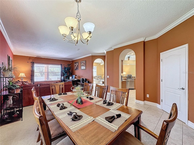 dining area with a textured ceiling, arched walkways, an inviting chandelier, light tile patterned flooring, and crown molding