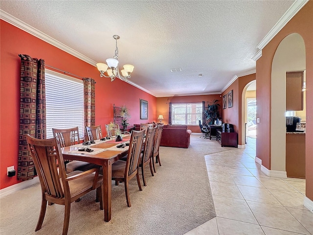 dining room with visible vents, crown molding, light carpet, light tile patterned flooring, and arched walkways