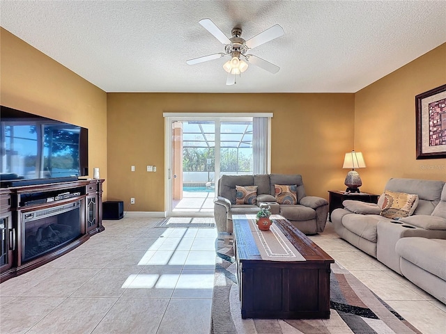 living room featuring baseboards, a textured ceiling, light tile patterned flooring, and a ceiling fan