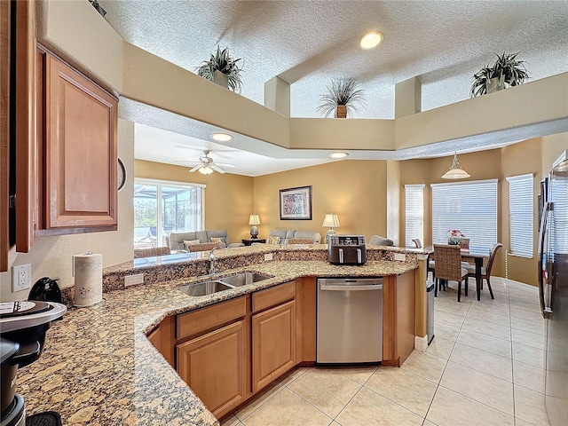 kitchen with a sink, light stone counters, light tile patterned floors, dishwasher, and ceiling fan