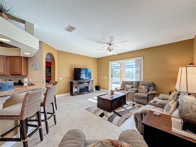 living area with arched walkways, visible vents, a textured ceiling, and light tile patterned floors