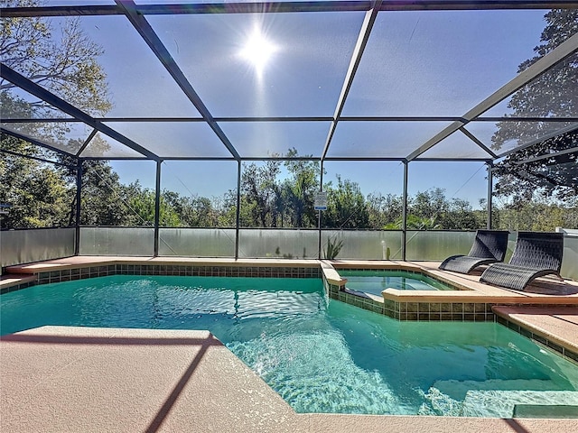 view of swimming pool featuring glass enclosure, a patio, and a pool with connected hot tub