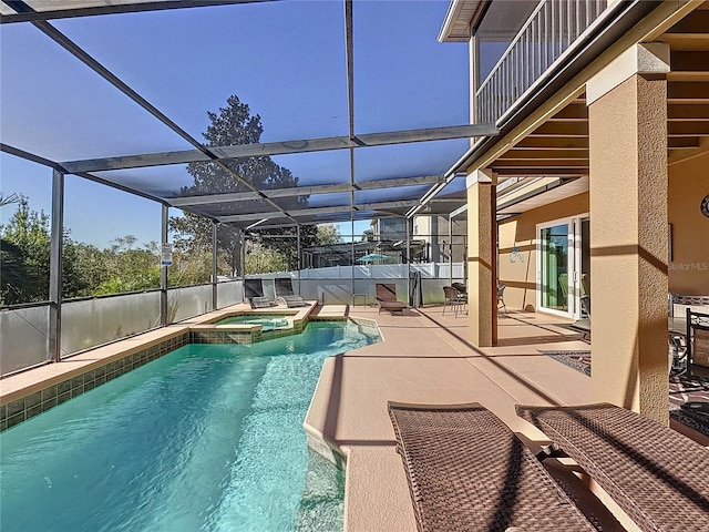 view of pool featuring a patio area, glass enclosure, and a pool with connected hot tub