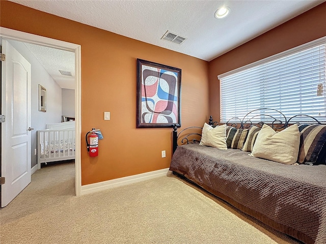 bedroom with visible vents, baseboards, a textured ceiling, and carpet flooring