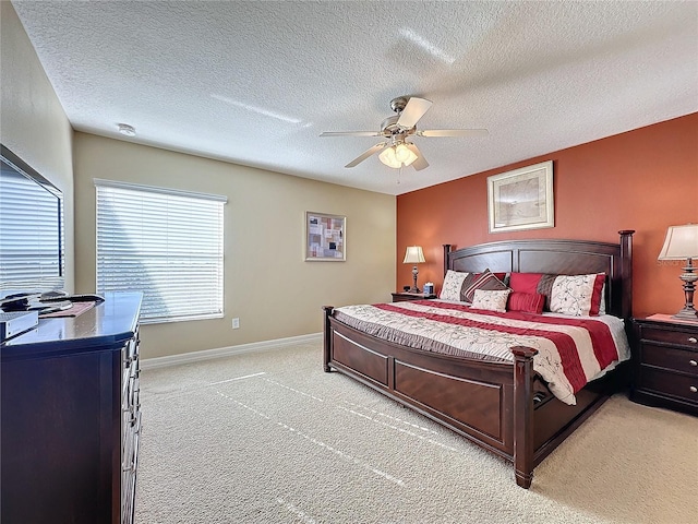 bedroom with light colored carpet, a textured ceiling, a ceiling fan, and baseboards