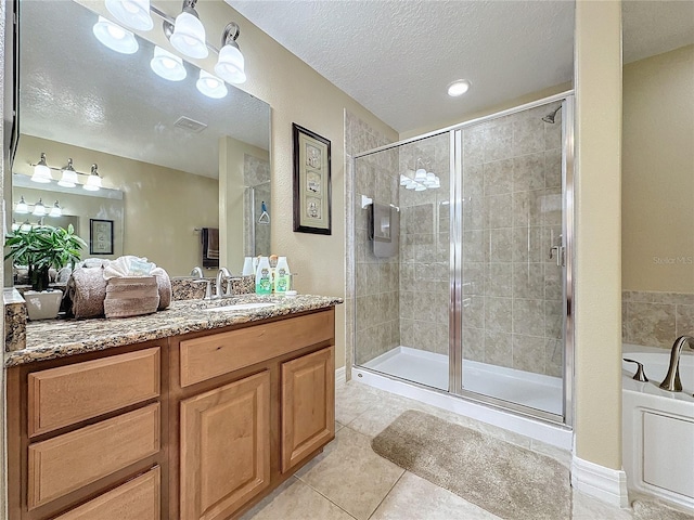 bathroom with tile patterned flooring, a shower stall, a textured ceiling, and vanity