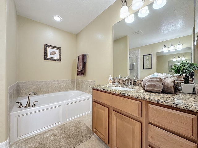 bathroom featuring vanity, visible vents, a stall shower, a textured ceiling, and a garden tub