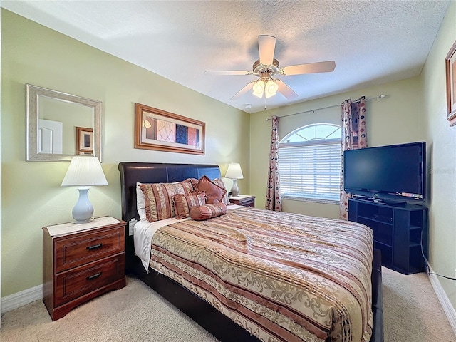 bedroom with baseboards, light colored carpet, a ceiling fan, and a textured ceiling