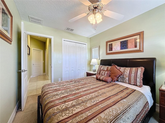 bedroom with visible vents, a textured ceiling, a closet, baseboards, and light colored carpet