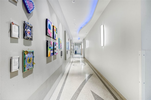 hallway with baseboards and speckled floor