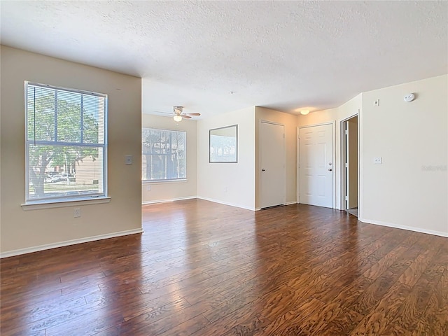 empty room featuring baseboards, dark wood-type flooring, and a textured ceiling