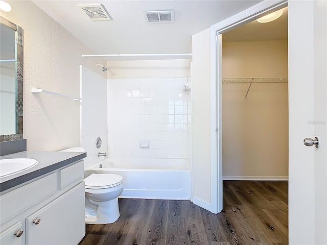 bathroom with bathtub / shower combination, toilet, wood finished floors, and visible vents