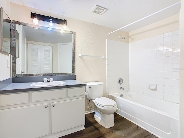 bathroom featuring vanity, washtub / shower combination, wood finished floors, visible vents, and toilet