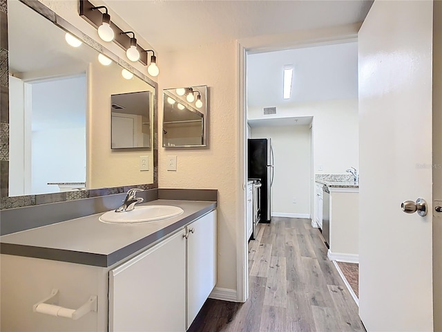 bathroom featuring visible vents, baseboards, wood finished floors, and vanity