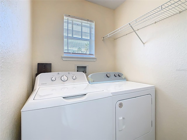 clothes washing area with washer and dryer, laundry area, and a textured wall