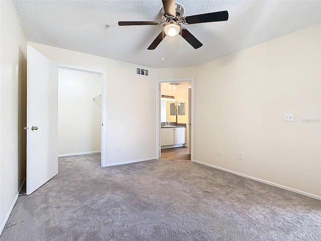 unfurnished bedroom featuring a spacious closet, visible vents, carpet flooring, and a textured ceiling