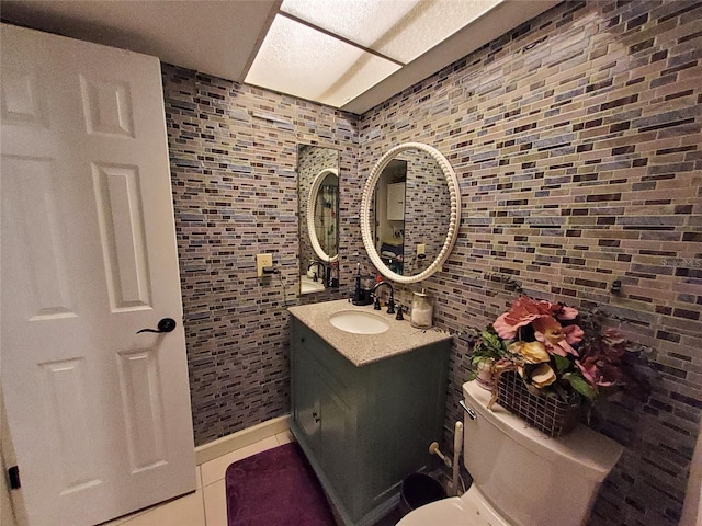 half bath featuring tasteful backsplash, toilet, vanity, tile patterned floors, and tile walls