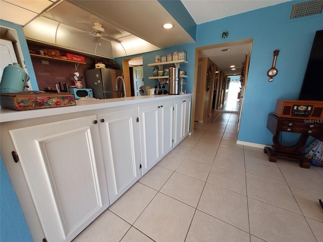 kitchen with visible vents, open shelves, freestanding refrigerator, light tile patterned flooring, and white cabinets