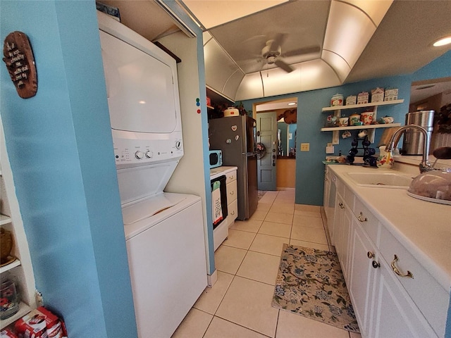 interior space featuring a sink, light tile patterned flooring, white cabinetry, stacked washer / drying machine, and open shelves