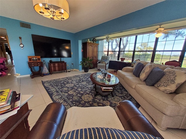 tiled living room featuring ceiling fan with notable chandelier, visible vents, a wealth of natural light, and baseboards