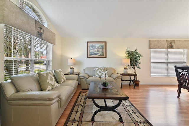 living room featuring vaulted ceiling, baseboards, and wood finished floors