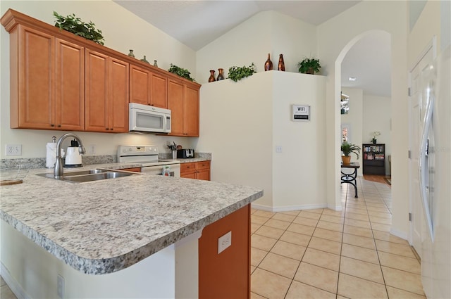 kitchen featuring a sink, white appliances, arched walkways, a peninsula, and light countertops