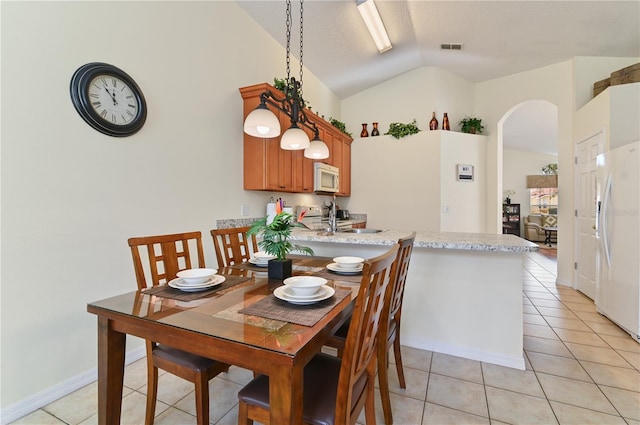 dining area with visible vents, vaulted ceiling, light tile patterned floors, arched walkways, and a textured ceiling