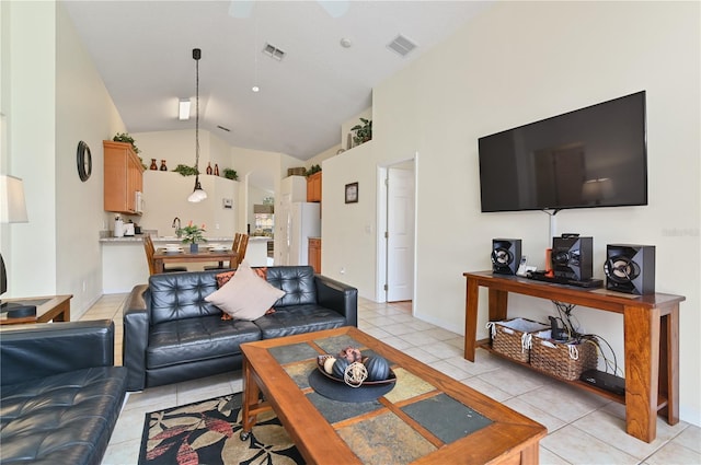 living area featuring light tile patterned floors, visible vents, and vaulted ceiling