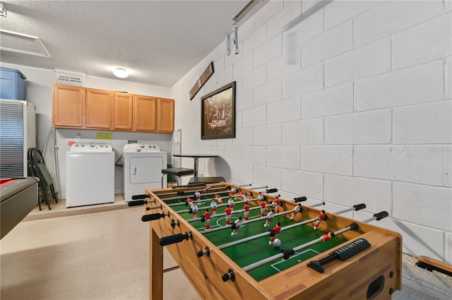 recreation room with concrete block wall, washing machine and dryer, concrete flooring, and a textured ceiling