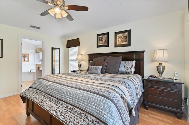 bedroom with visible vents, baseboards, light wood-style floors, and connected bathroom